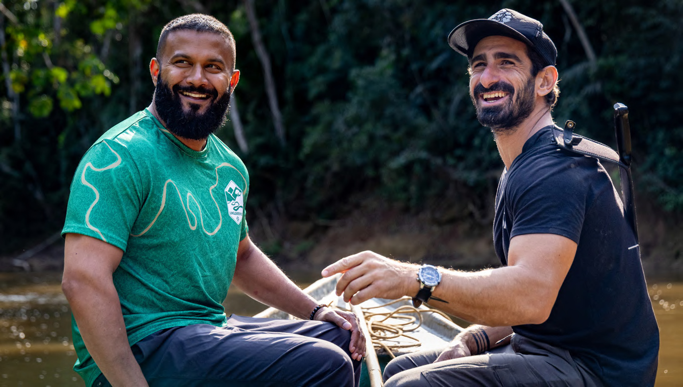 Dax Dasilva and Paul Rosolie seated together in a boat on a river in the Peruvian Amazon