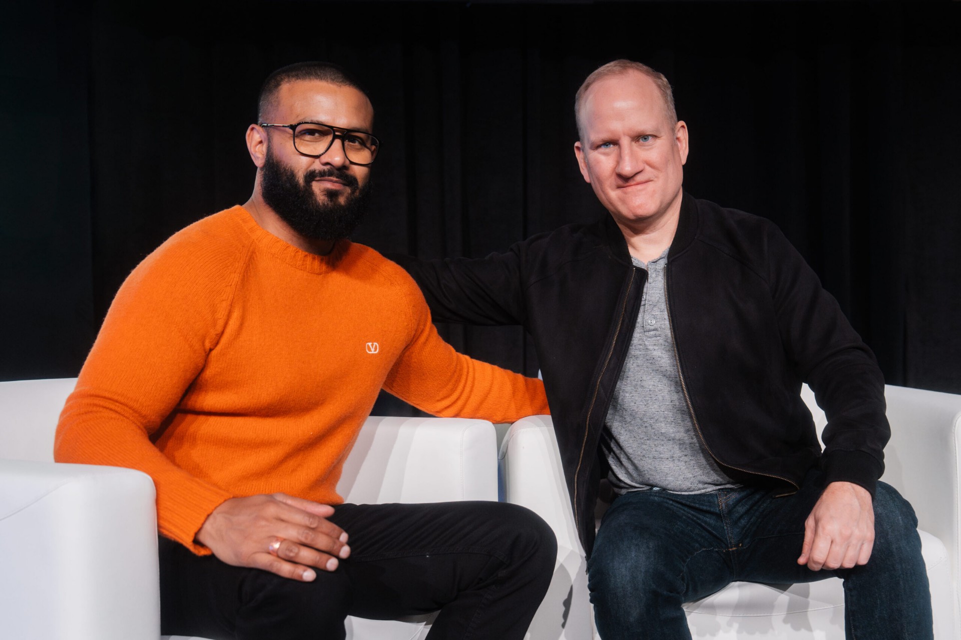 Two men seated on a panel stage discussing the Re:wild partnership